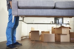 Man Carrying Sofa As He Moves Into New Home